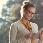 closeup of happy woman in glasses using tablet pc in the park